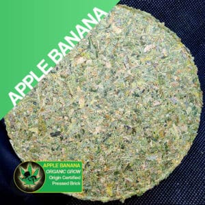 Close up photo of the pressed brick cannabis strain Apple Banana. Text next to the flower states the name of the strain, that it is organically grown, and pressed brick weed.