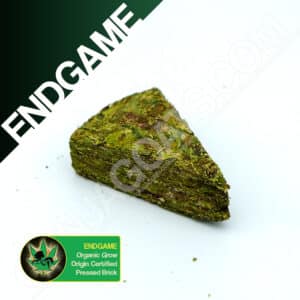 Close up photo of the pressed brick cannabis strain Endgame. Text next to the flower states the name of the strain, that it is organically grown, and pressed brick weed.