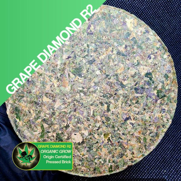 Close up photo of the pressed brick cannabis strain Grape Diamond R2. Text next to the flower states the name of the strain, that it is organically grown, and pressed brick weed.